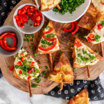 Pita chips decorated like Christmas trees with red pepper, parsley, and a pretzel as a trunk.