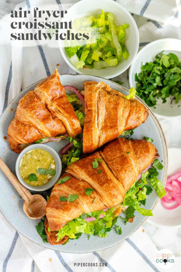 A croissant sandwich with cheese, lettuce, and pickled red onions with a text title for Pinterest.