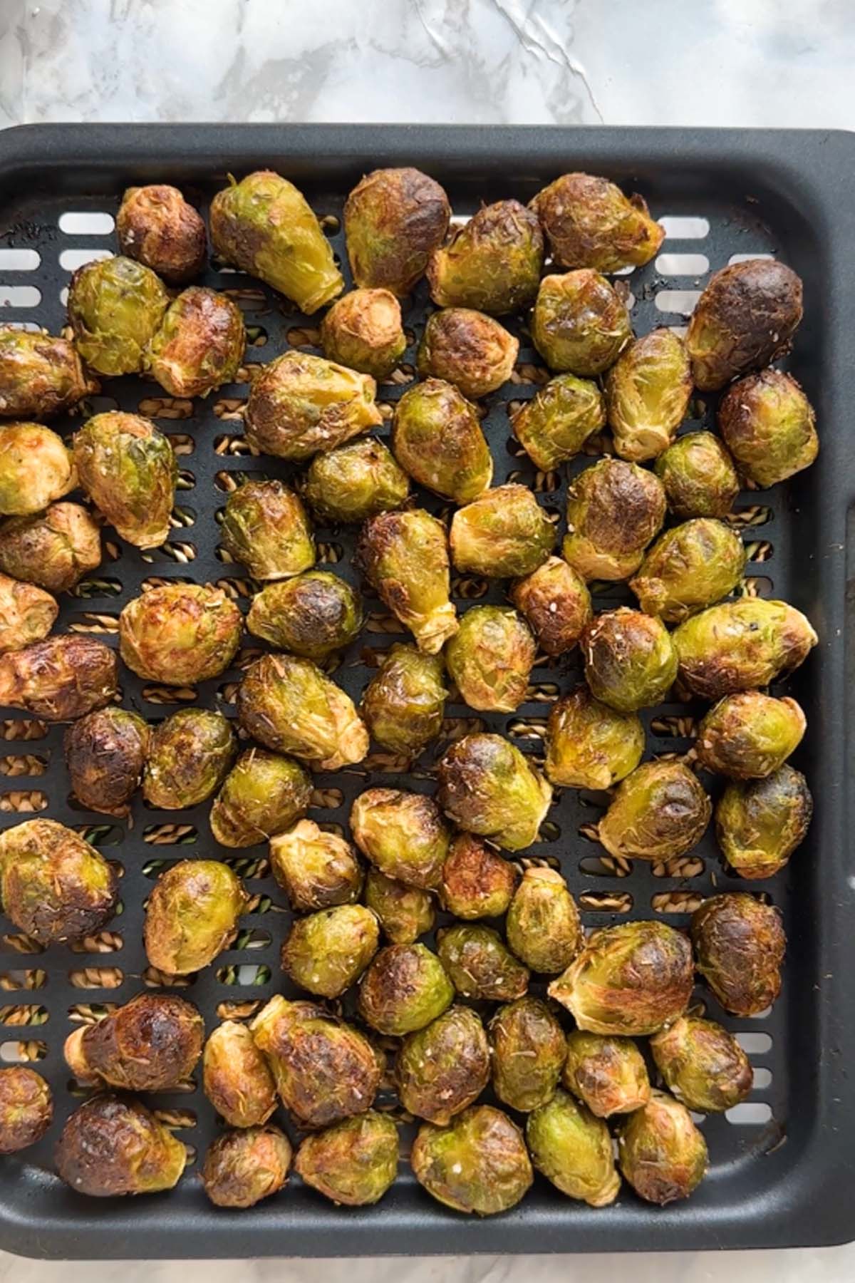 Cooked Brussels sprouts on an air fryer tray.