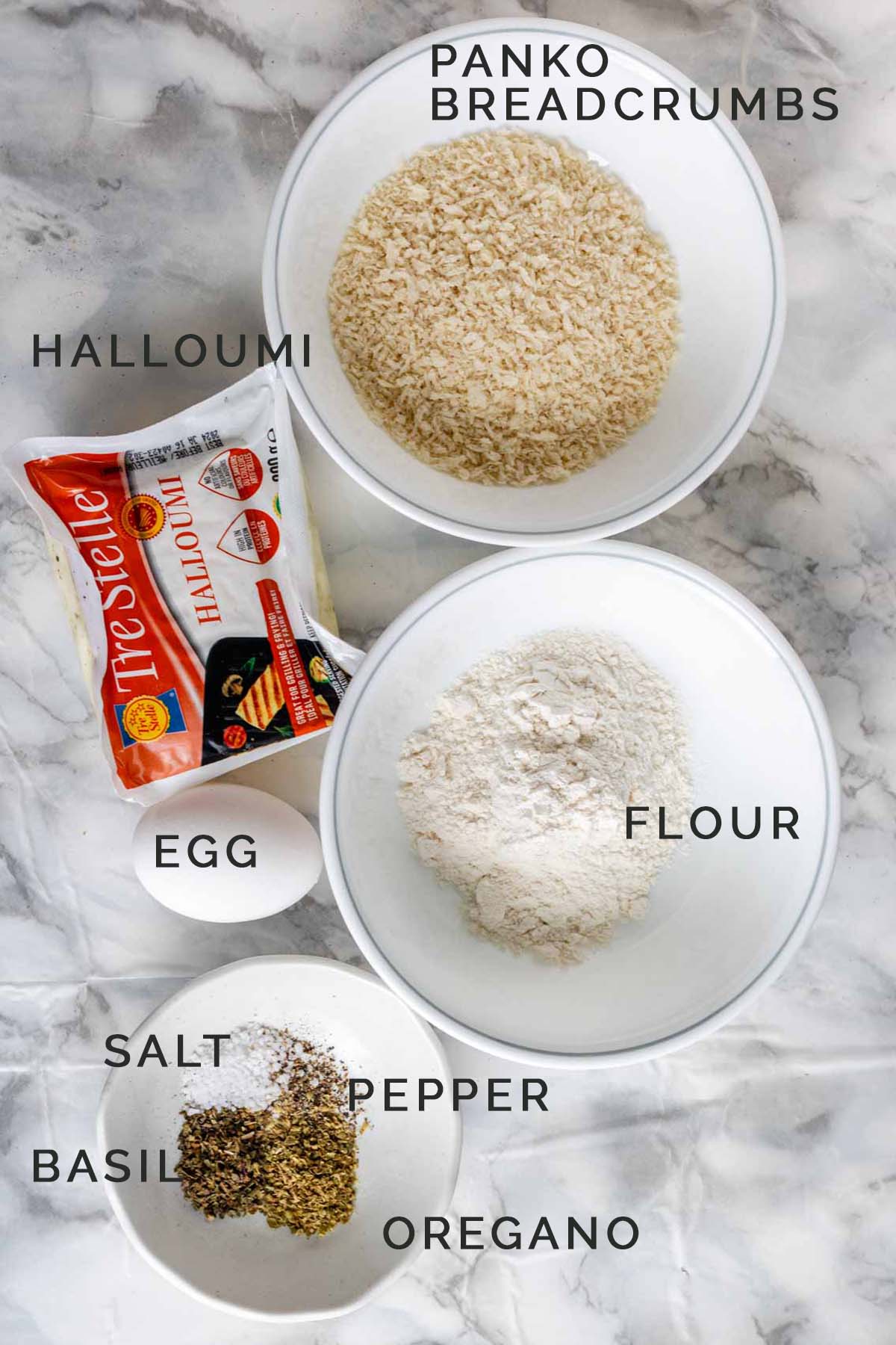 Ingredients for breaded halloumi on a white marble counter.
