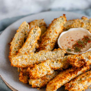 Air-fried breaded pickles on a plate with a bowl of dip.