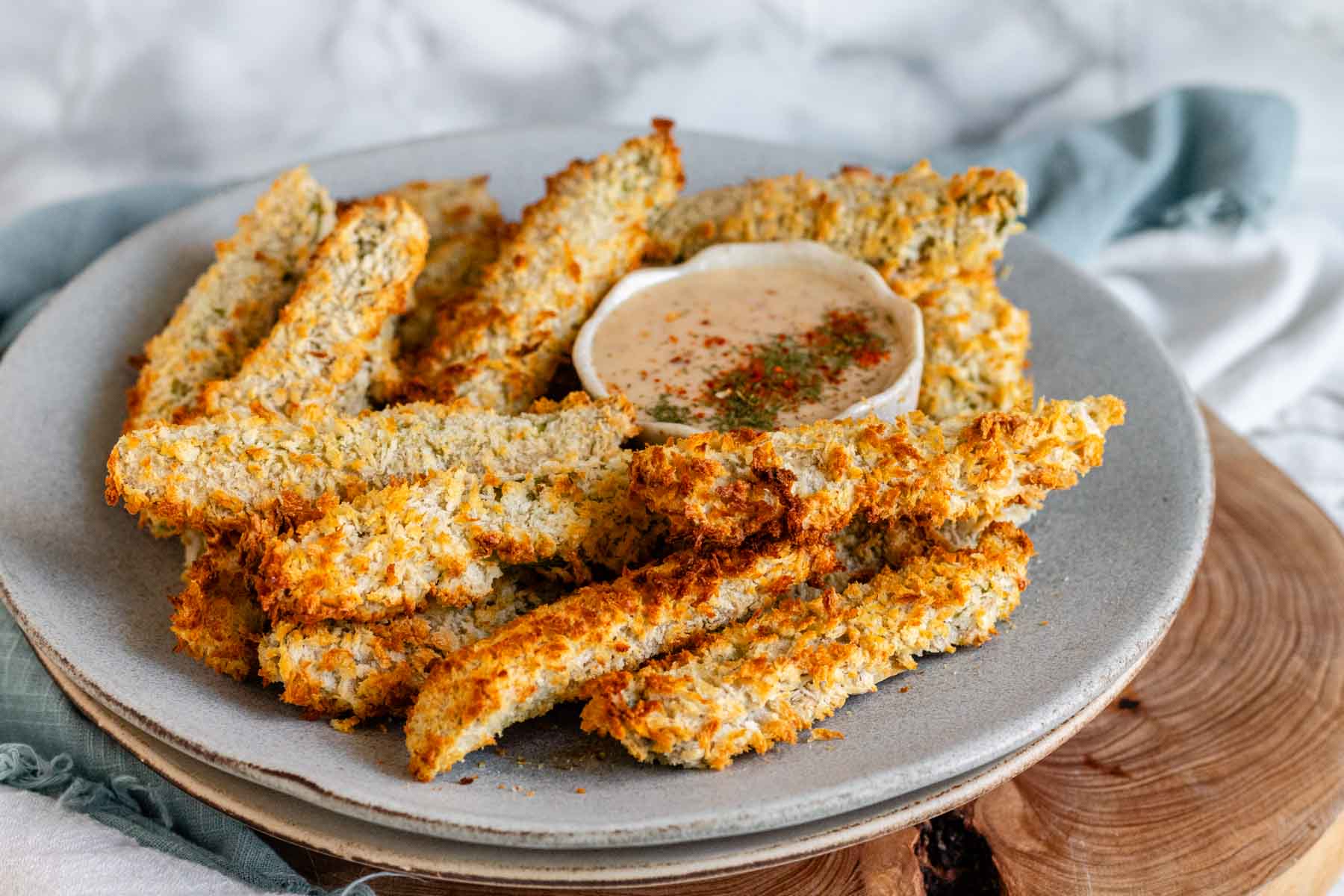 Air-fried breaded pickles on a plate with a bowl of dip.