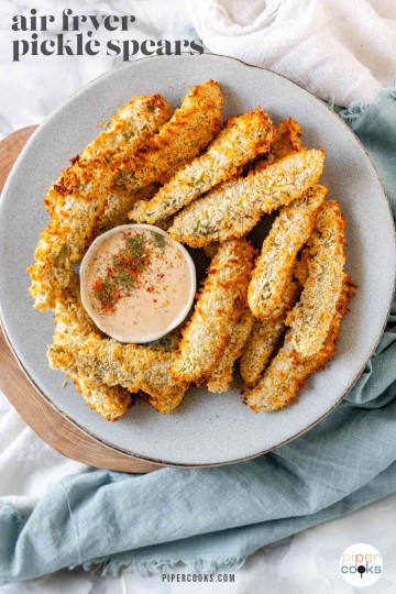 Air-fried breaded pickles on a plate with a bowl of dip with text for Pinterest.