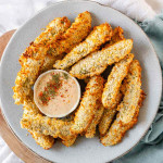 Air-fried breaded pickles on a plate with a bowl of dip.