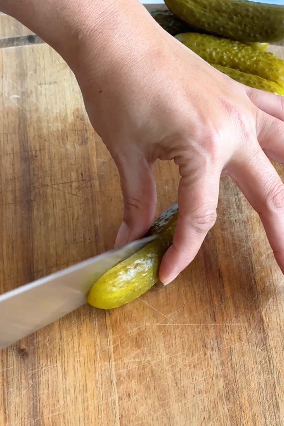 A pickle is sliced in half with a knife.