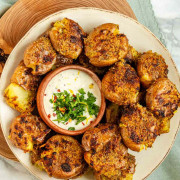 Smashed potatoes on a plate with a bowl of dip with text title for Pinterest.