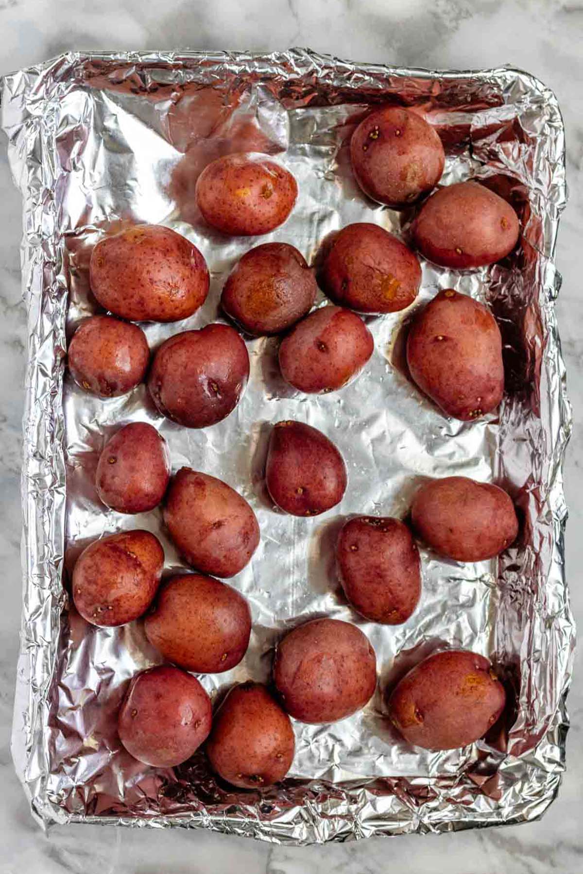 Baby potatoes on a foil-lined baking sheet.