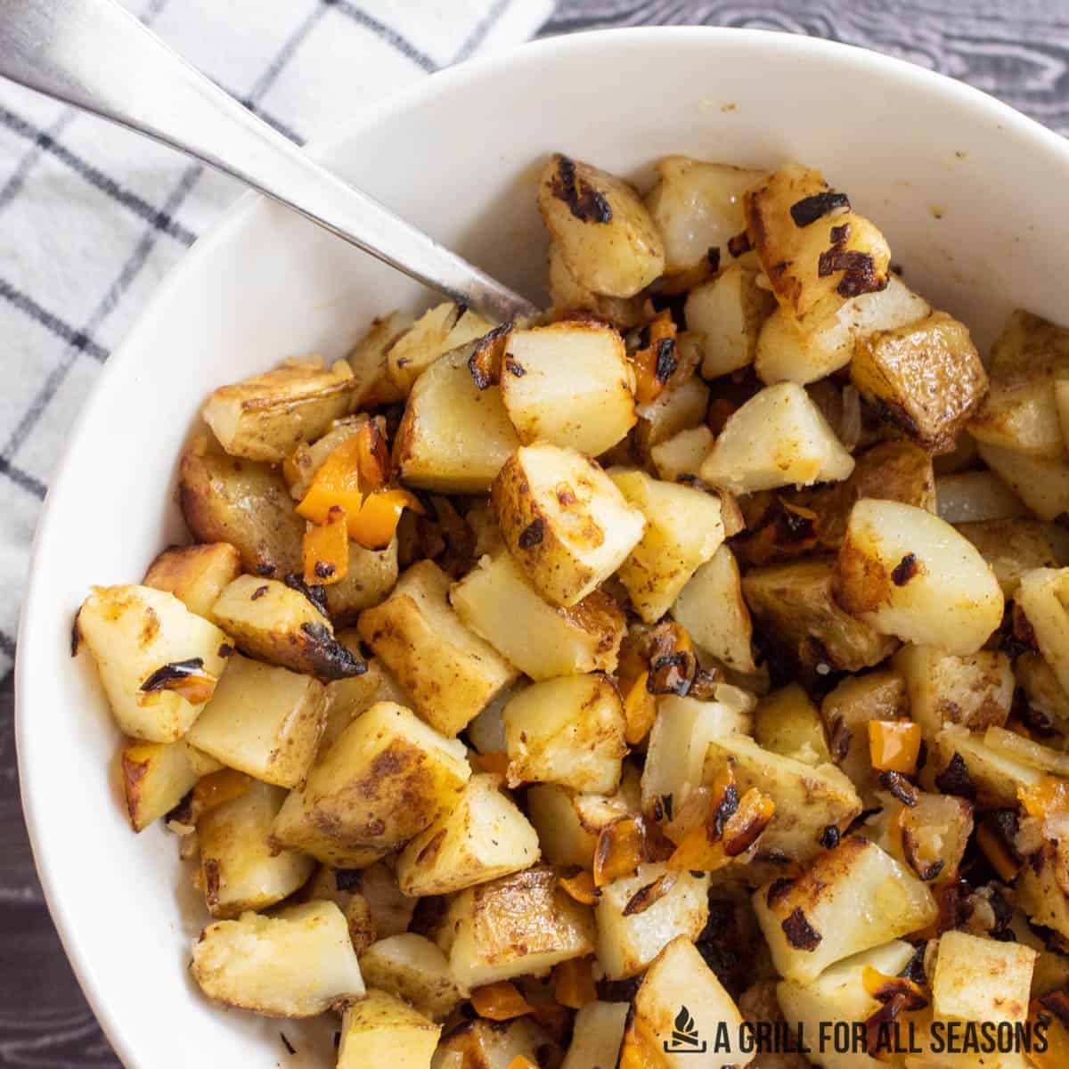 Cubed cooked potatoes with onions in a bowl.