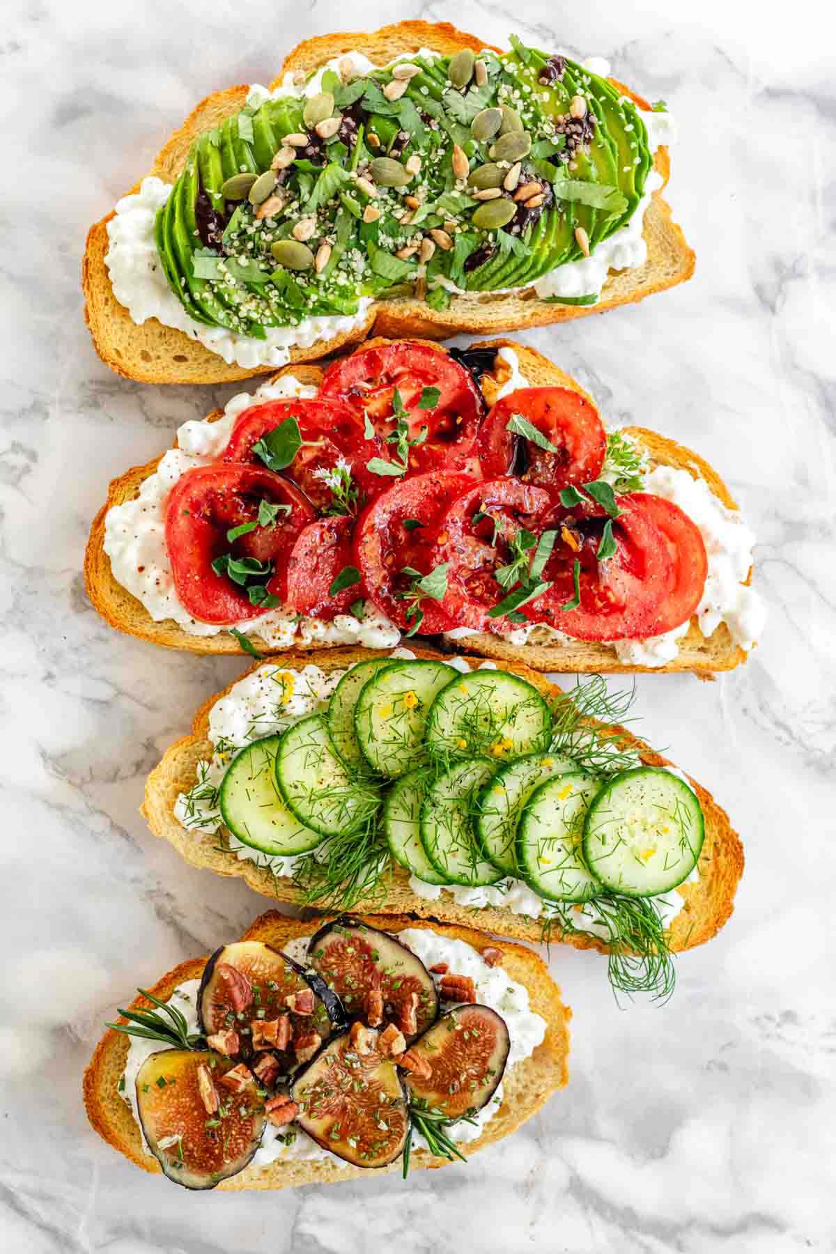 4 slices of cottage cheese toast with different toppings like avocado, cucumber, tomato, and figs.