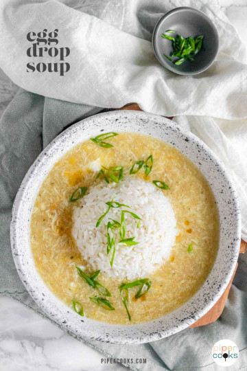 Egg drop soup in a bowl with a rounded ball of rice in the center and green onions on top with a text title for Pinterest.