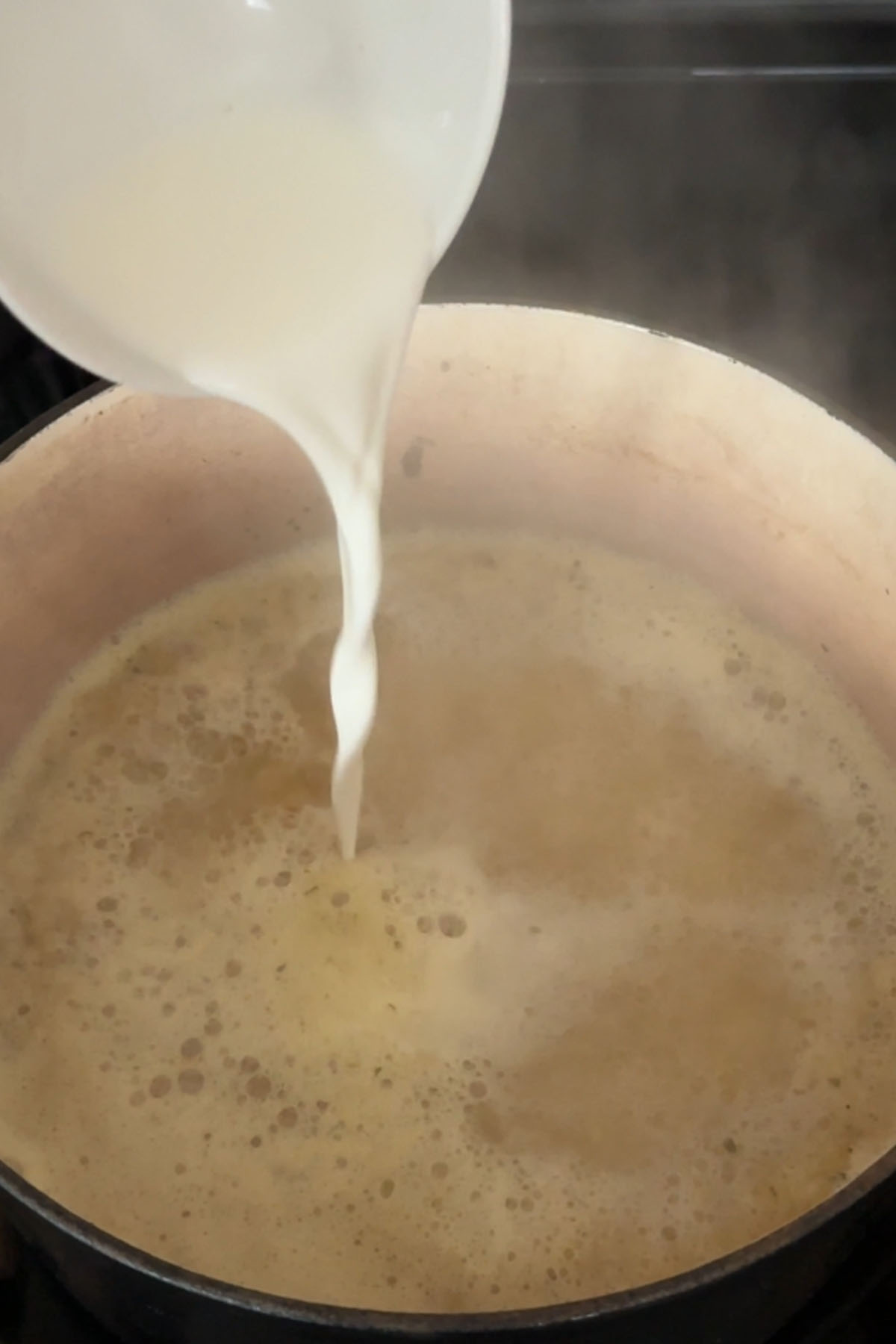 A cornstarch slurry is poured into steaming broth.
