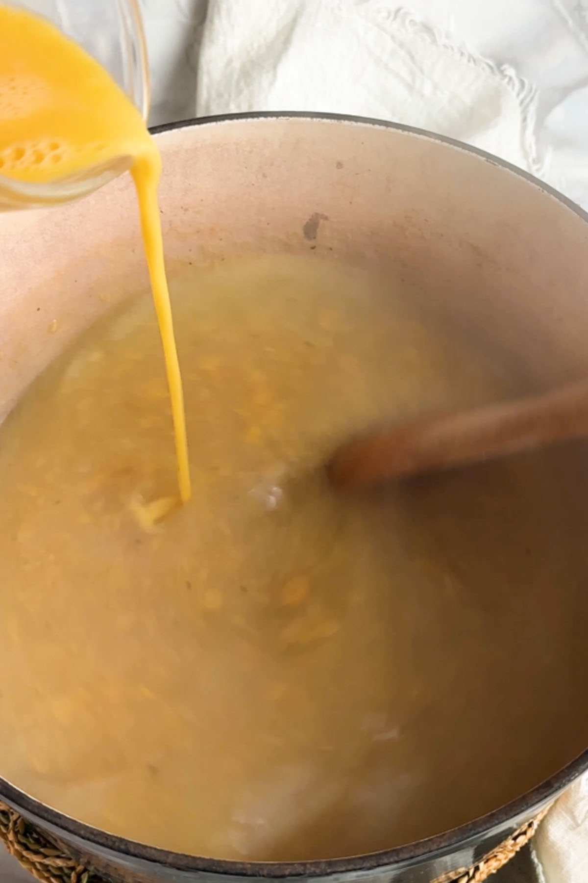 Eggs are poured in a thin line into broth.