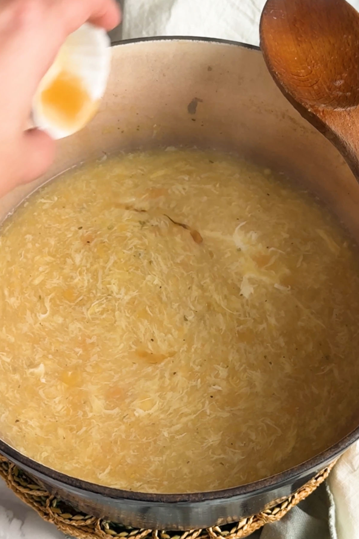 Sesame oil is poured into a pot of egg drop soup.