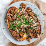 Toast on a plate topped with mushrooms, cheese, and parsley.