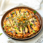 A potato pizza topped with balsamic glaze, chickpeas, and broccoli sprouts.
