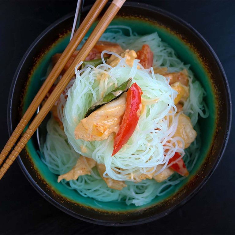 Vegetables and noodles in a bowl with chopsticks.