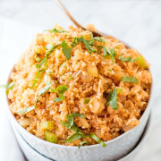 Orange cauliflower rice in two stacked white bowls with text for Pinterest.