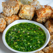 Bright green chimichurri sauce in a bowl surrounded by air-fried breaded paneer with a text title for Pinterest.