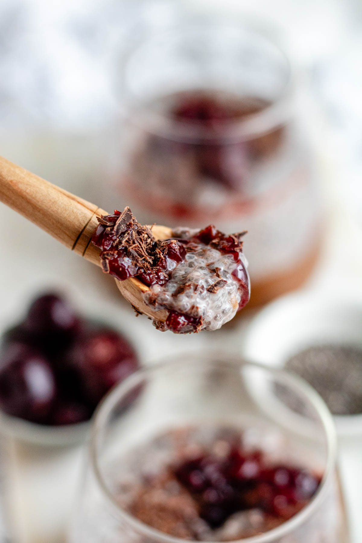Chocolate cherry chia pudding on a wooden spoon.