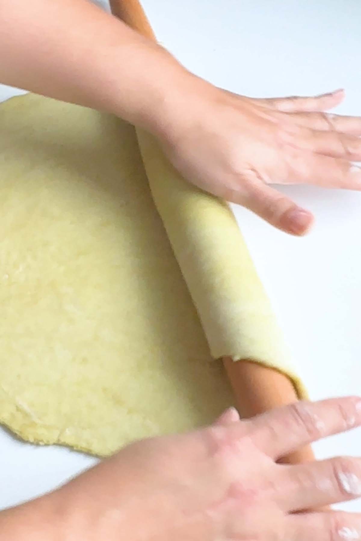 Pie dough is rolled onto a rolling pin.