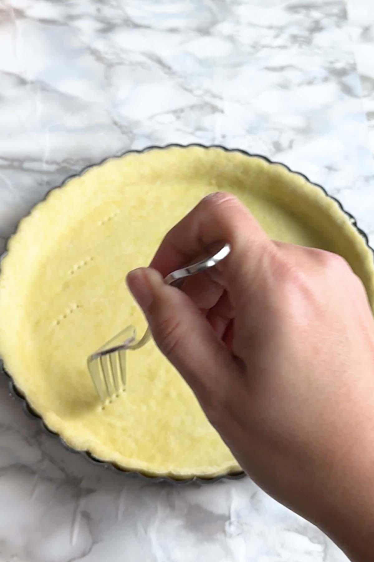 Pie dough is poked with a fork.