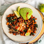 Cubed sweet potato, a fried egg, avocado, and lime wedges on a plate.