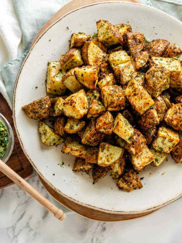 Crispy cubed potatoes on a plate, coated in a seasoning mix.