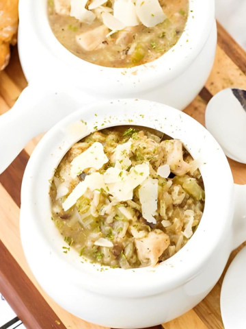Chicken, rice, and mushrooms in a white pot with a handle.