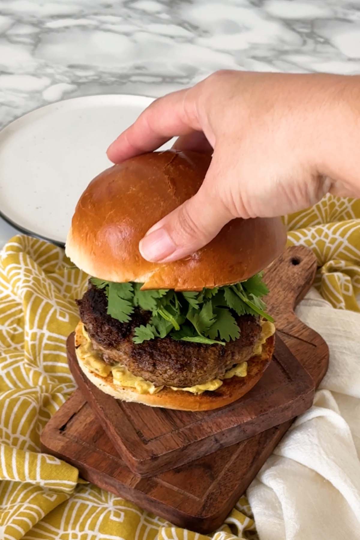 A top bun is added to a burger to close it.