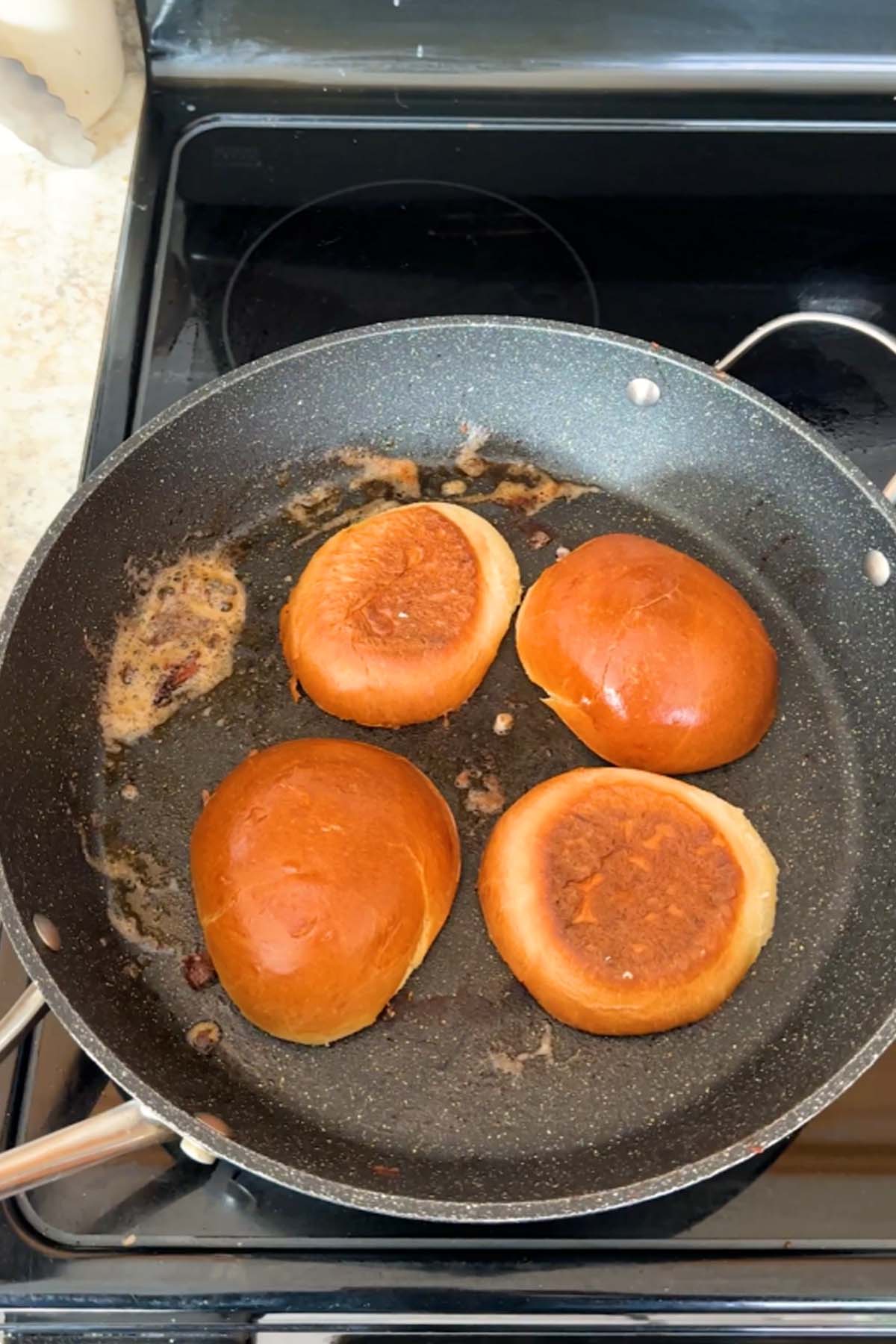 Burger buns are toasted in a skillet.