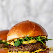 A burger with yellow sauce and cilantro leaves with the text 'burgers with curry sauce'.