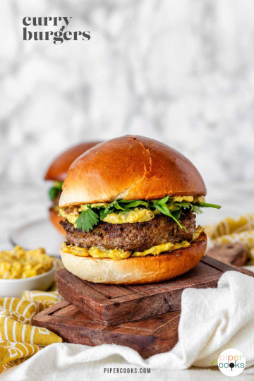 A burger with yellow sauce and cilantro leaves with the text 'curry burgers'.