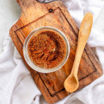 Seasoning mix in a jar beside a wooden spoon.