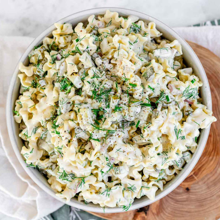 Pasta salad in a bowl topped with fresh dill.