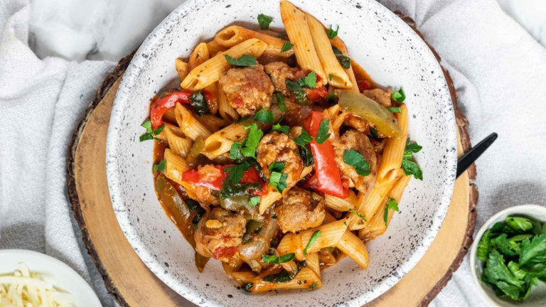 Pasta and sausage in a bowl topped with parsley.
