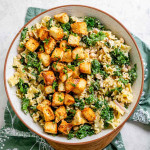 Pasta and greens in a bowl topped with croutons.
