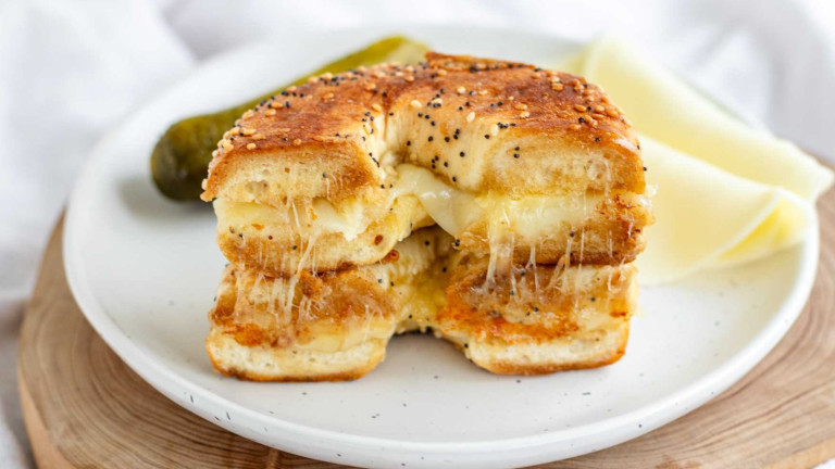 A stacked halved sandwich filled with melted cheese.
