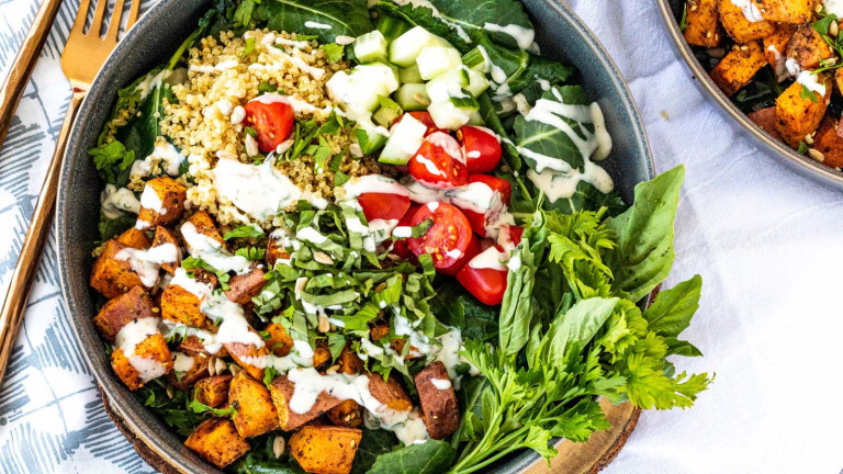 A bowl with grains and vegetables drizzled with sauce.
