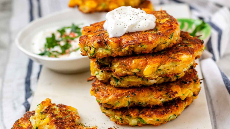 Stacked vegetable fritters topped with a dollop of yogurt.