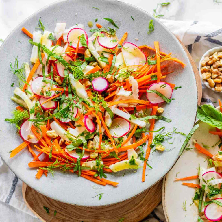 Sliced vegetables on plates topped with fresh herbs and a fork.