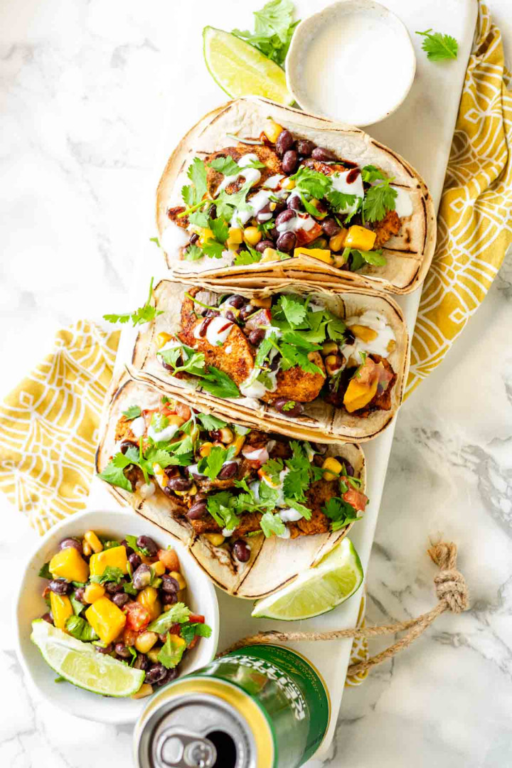 Soft tacos with white corn tortillas, chicken, mango, black beans, and cilantro.