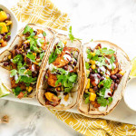 Soft tacos with white corn tortillas, chicken, mango, black beans, and cilantro.