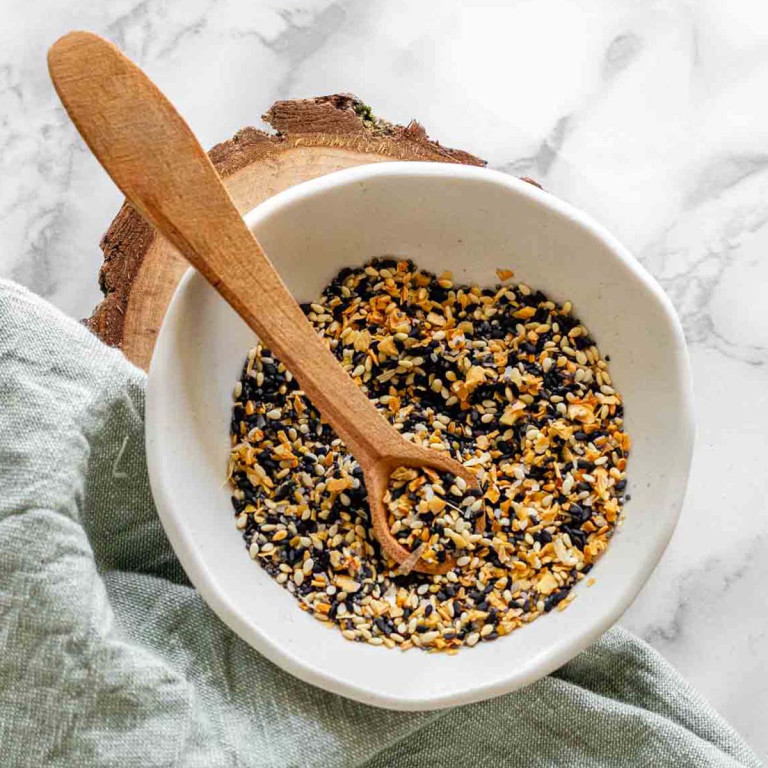 A bowl of mixed seeds with a wooden spoon in it.