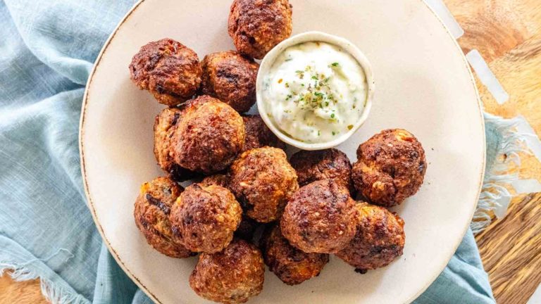 Meatballs on a plate with a bowl of dip.