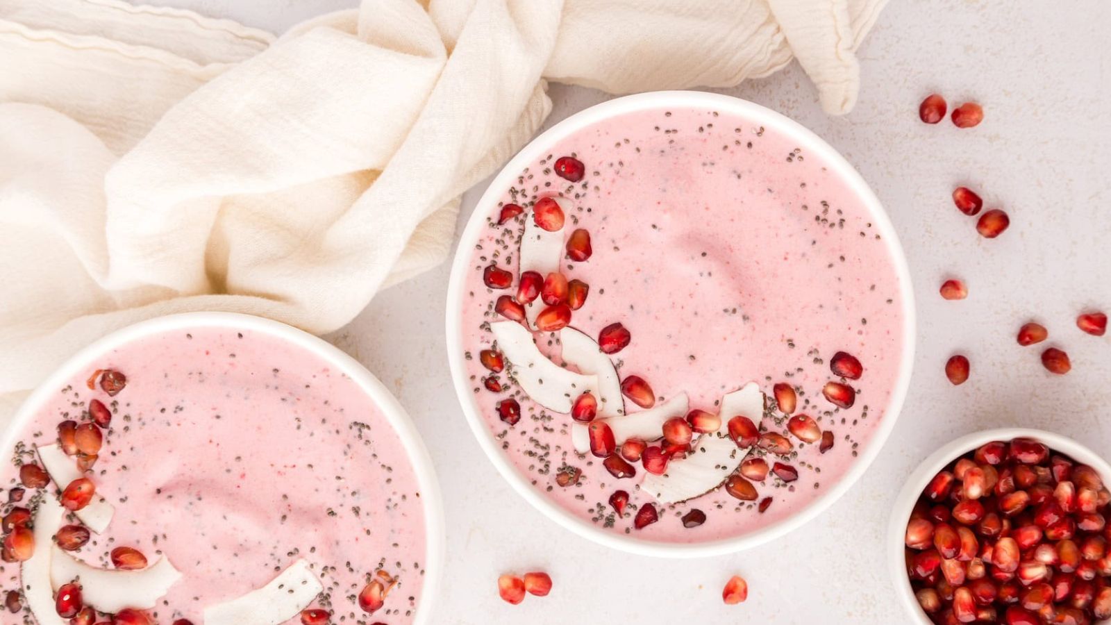 A pink smoothie bowl topped with coconut and pomegranate arils.