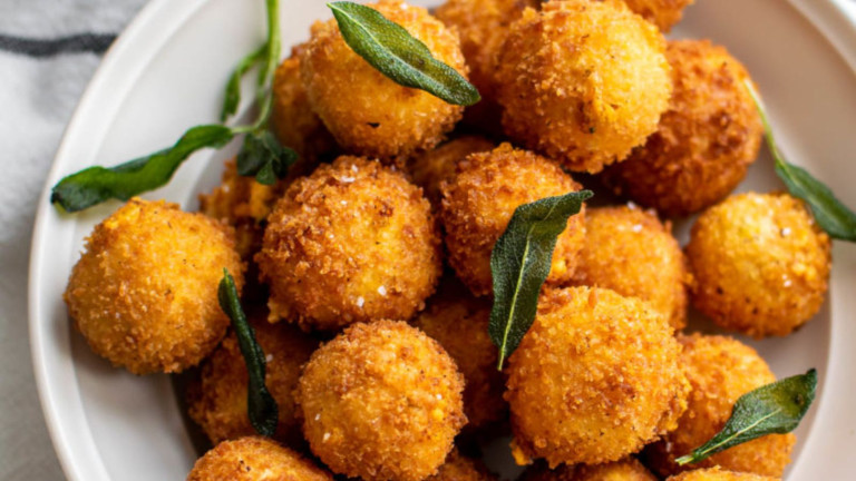 Round breaded appetizers topped with sage leaves.