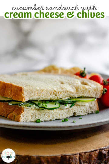 A sandwich with cucumbers beside tomatoes on a plate with the text cucumber sandwich with cream cheese and chives.
