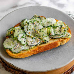 Cucumber salad with seeds on top of toast on a plate.