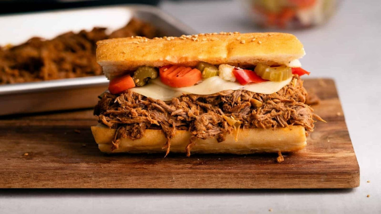 A sandwich stuffed with shredded meat, cheese, and vegetables.