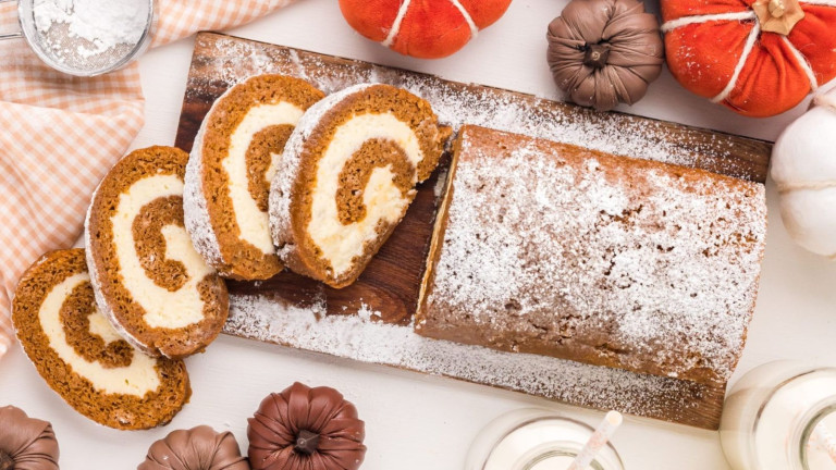 A pumpkin swirl cake topped with icing sugar, surrounded by crafted pumpkins.